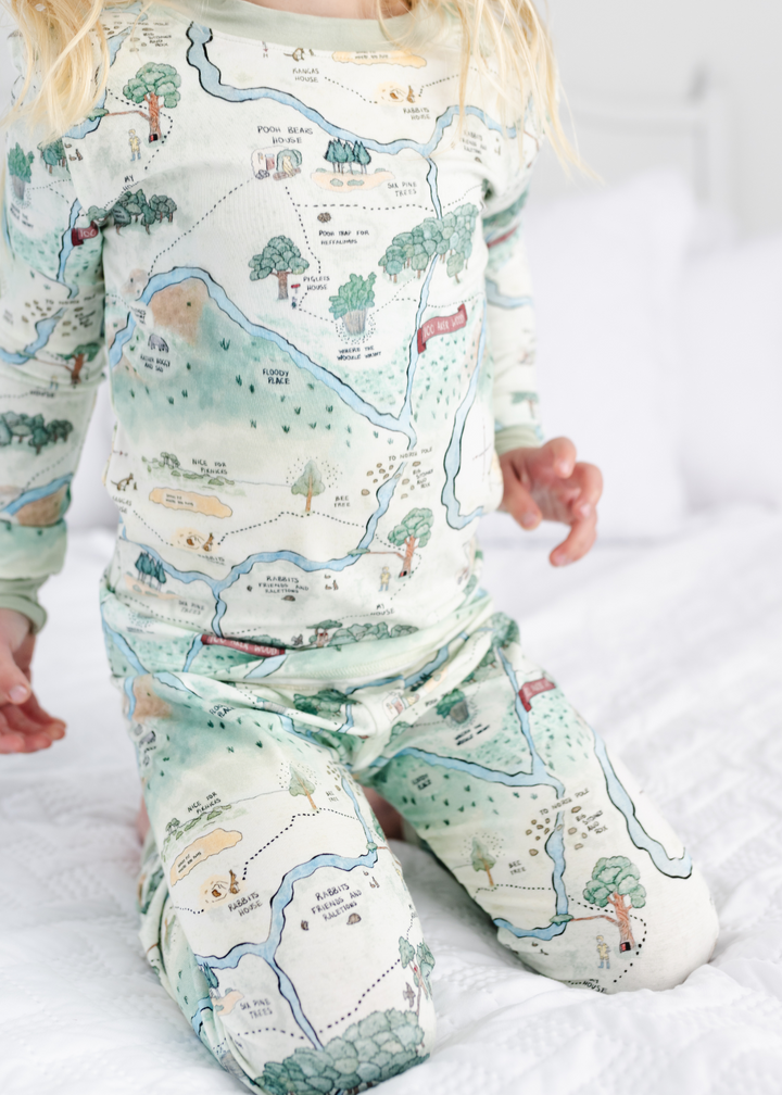 Hundred Acre Woods Winnie the Pooh map design in two piece pajamas for babies. Close up model shot