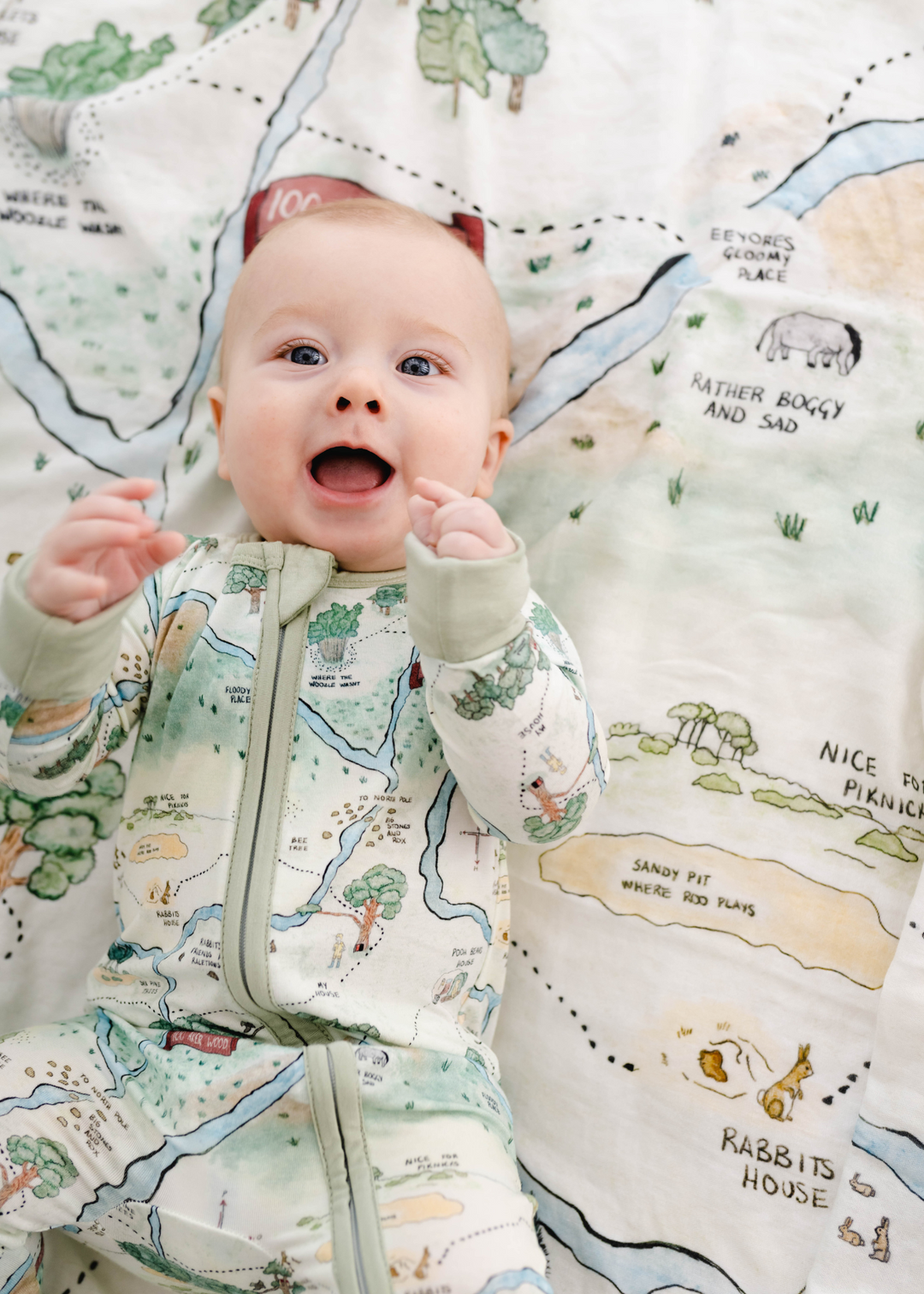 Hundred Acre Woods bamboo baby sleeper with adorable baby. Adorable baby in Winnie the Pooh map zippered sleeper.