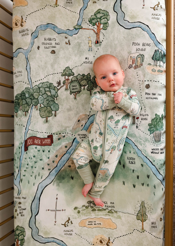 Hundred Acre Woods crib sheet with baby in crib. Winnie the Pooh map themed crib sheet with baby in crib.