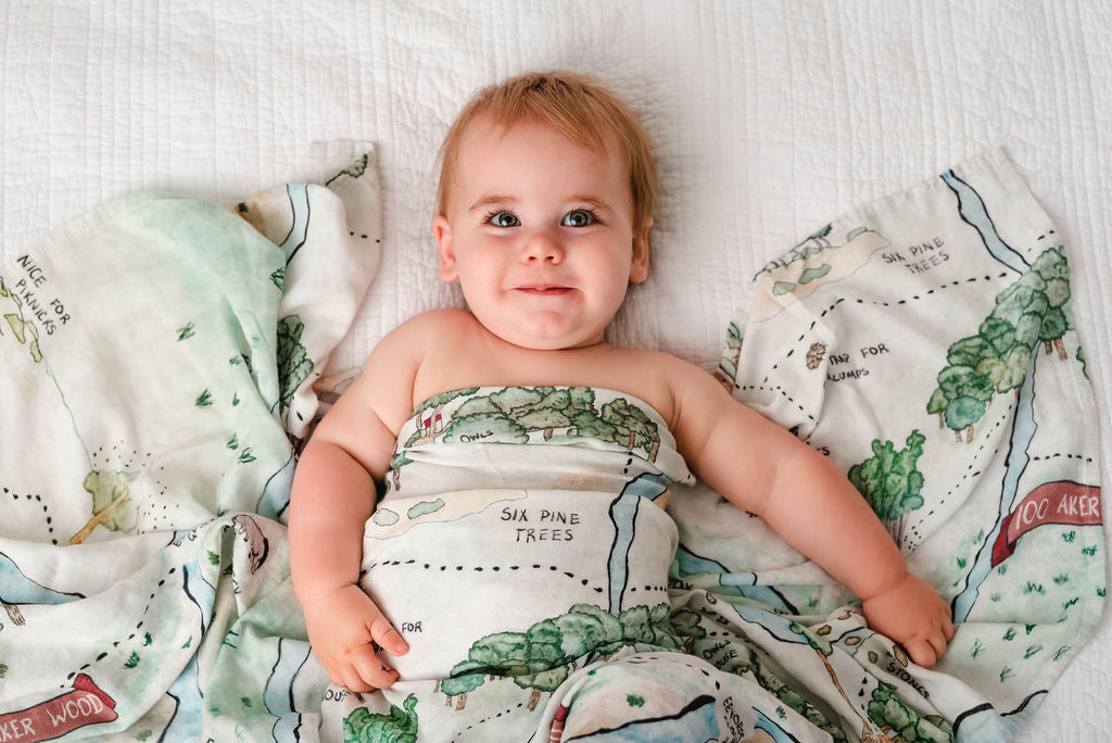 Hundred Acre Woods swaddle with baby. Winnie the Pooh map themed swaddle blanket baby.