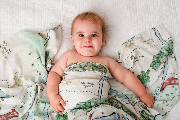 Hundred Acre Woods swaddle with baby. Winnie the Pooh map themed swaddle blanket baby.