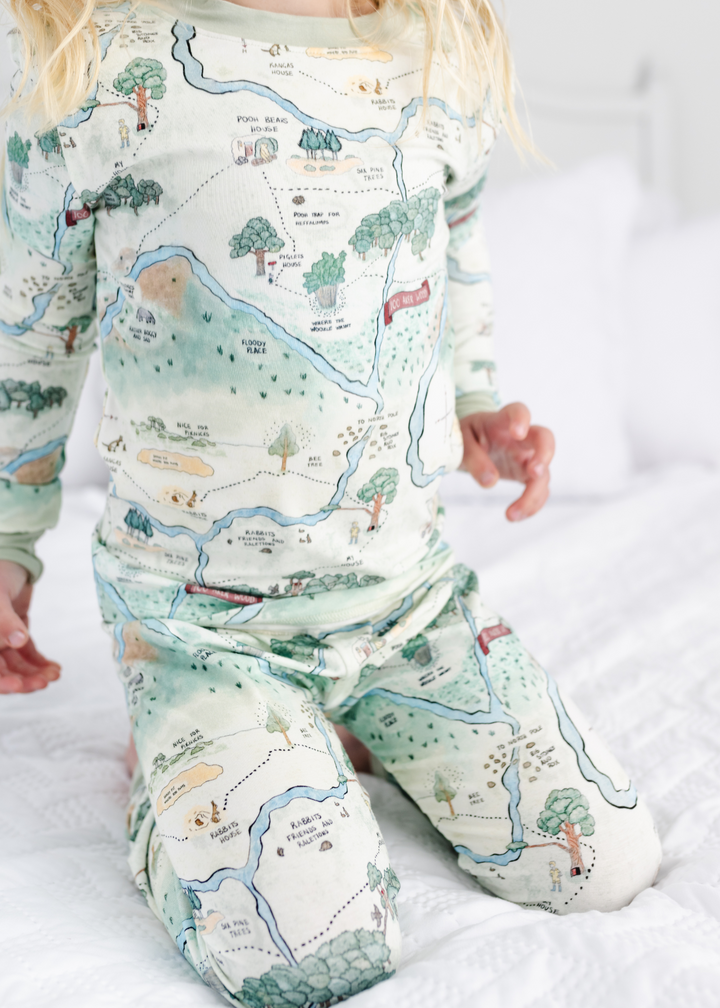 Hundred Acre Woods Winnie the Pooh map design in two piece pajamas for babies. Close up model shot 