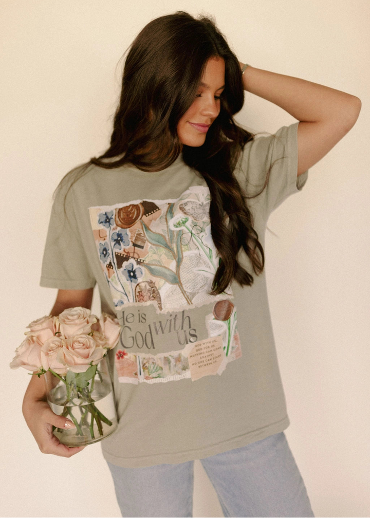 Woman wearing a t-shirt with floral design and text, holding flowers against a plain background