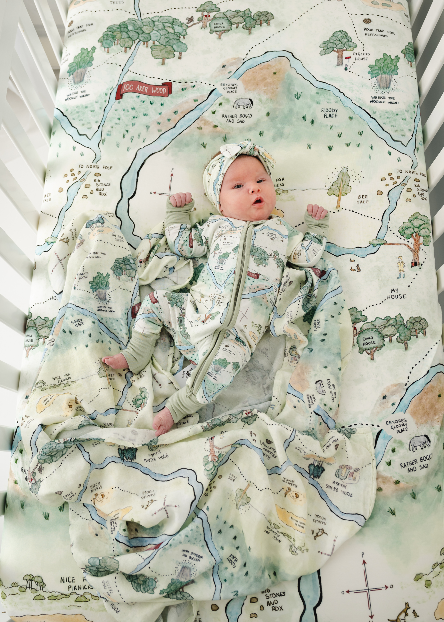 Hundred Acre Woods bamboo sleeper. Winnie the Pooh map bamboo zippered sleeper model photo with matching crib sheet and swaddle.