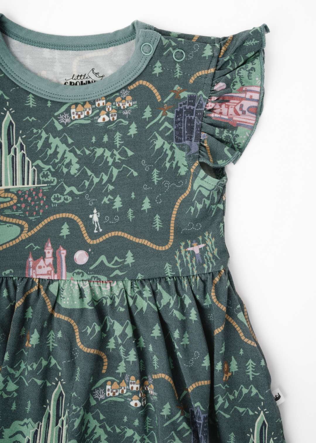 A closeup of a Wizard of Oz inspired baby dress outfit, with a yellow brick road and Wizard of Oz characters. The dress has snaps and flutter sleeves.