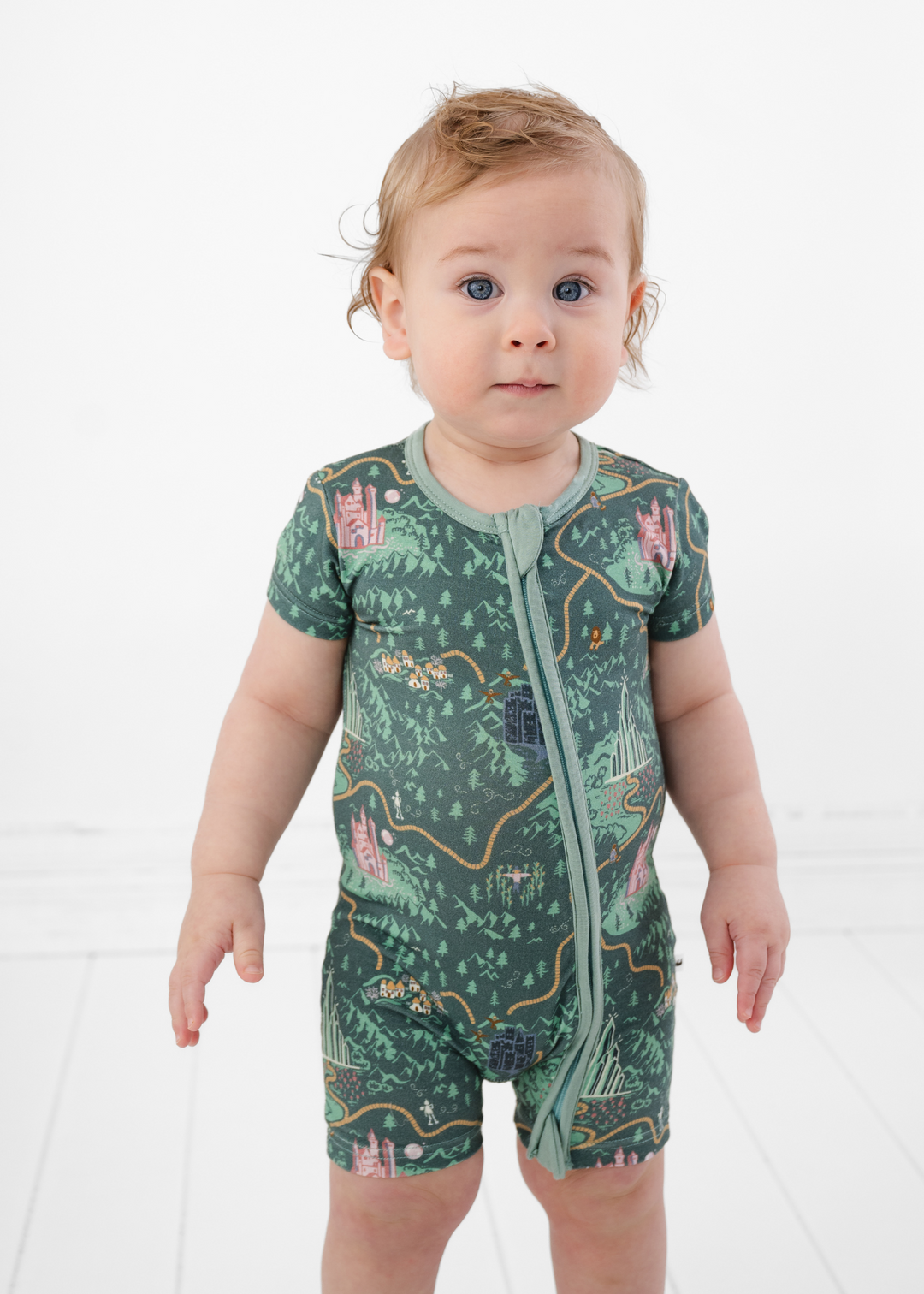 Emerald City Wizard of Oz themed baby bamboo outfit. Shortie Romper has a double zipper and is made from buttery soft bamboo fabric. Toddler is modeling the shortie romper outfit and the Wizard of Oz "Emerald City" design.