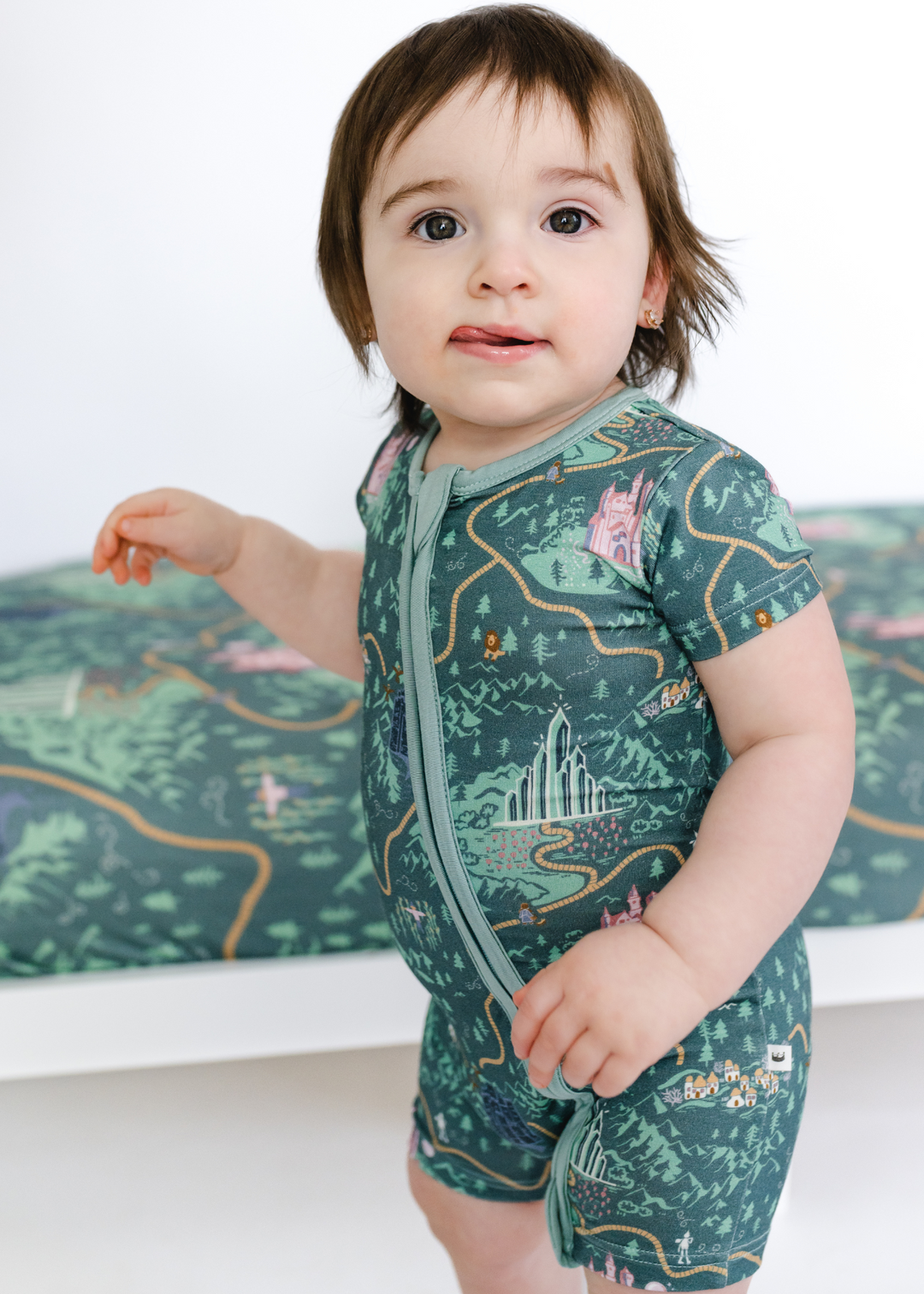 Wizard Of Oz bamboo shortie romper with double zippered on an Emerald City design with Wizard of Oz characters, yellow brick road and a green background.