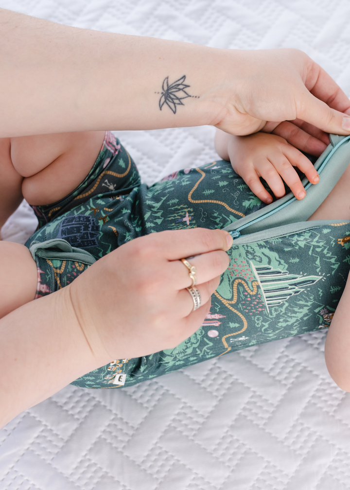 Our double zipper on our Shortie rompers with our Wizard of Oz inspired design featuring a yellow brick road, Wizard Of Oz characters, and a green background. 