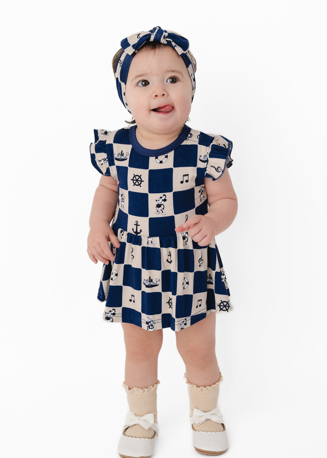 Baby wearing a navy and white checkered dress with nautical items and Steamboat Willie. Steamboat Willie dress for girls and babies!