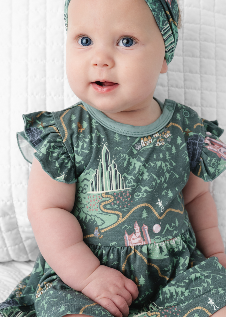 Baby in a Wizard of Oz short sleeve dress with Wizard of Oz characters, a yellow brick road and more!