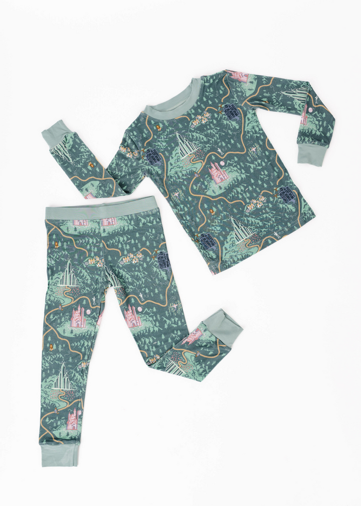 Wizard of Oz inspired pajamas on a deep green background featuring the Emerald City, Yellow Brick Road, and Wizard of Oz characters.