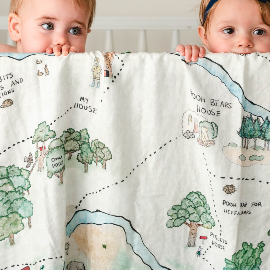 Hundred Acre Woods swaddle with babies. Winnie the Pooh map themed swaddle blanket babies in crib. 